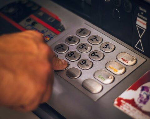 Mano presionando el teclado metálico de un cajero automático