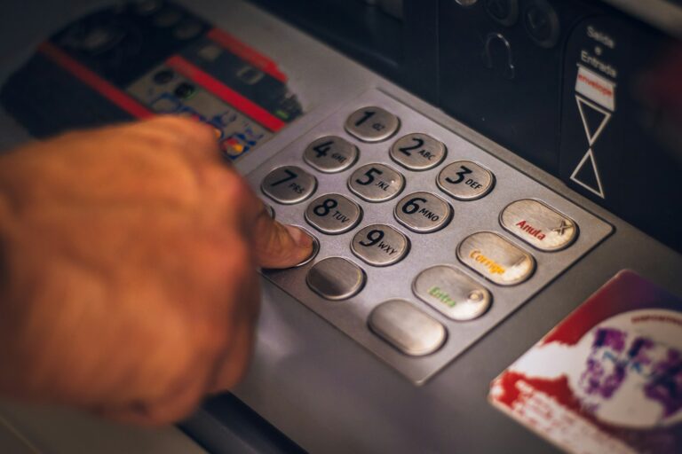 Mano presionando el teclado metálico de un cajero automático