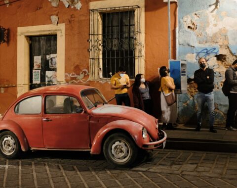 Automóvil rojo estacionado en una calle del centro de Oaxaca frente a una fachada colonial