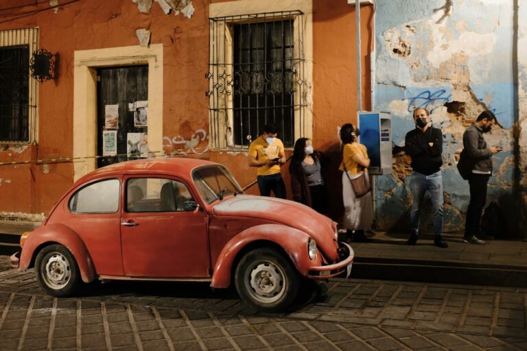 Automóvil rojo estacionado en una calle del centro de Oaxaca frente a una fachada colonial
