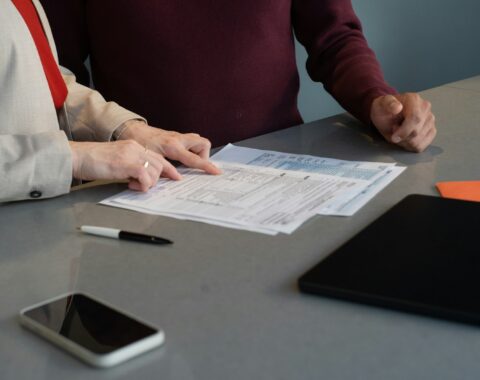 Dos personas revisan documentos sobre una mesa durante una reunión de trabajo