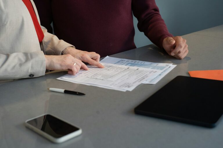 Dos personas revisan documentos sobre una mesa durante una reunión de trabajo