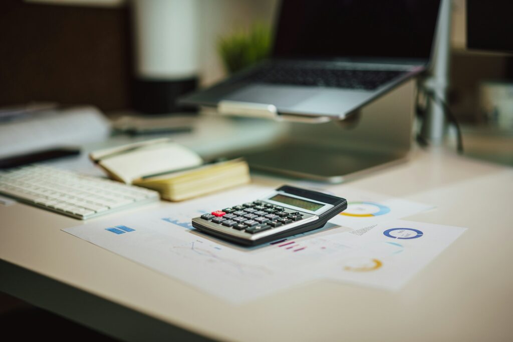 Calculadora sobre un escritorio junto a una laptop, imagen alusiva a las obligaciones fiscales del RESICO