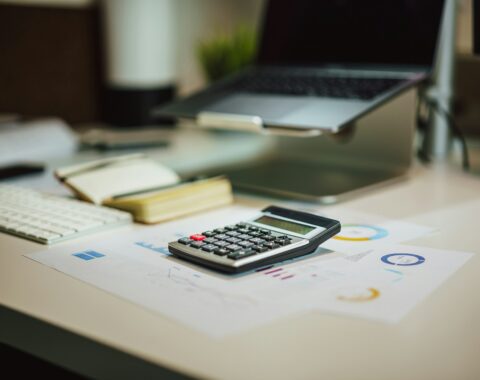 Calculadora sobre un escritorio junto a una laptop, imagen alusiva a las obligaciones fiscales del RESICO