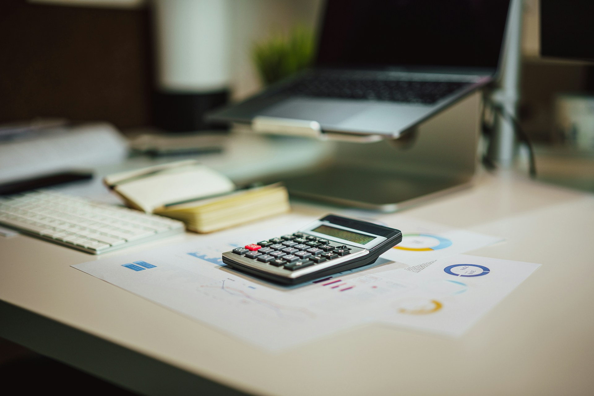 Calculadora sobre un escritorio junto a una laptop, imagen alusiva a las obligaciones fiscales del RESICO