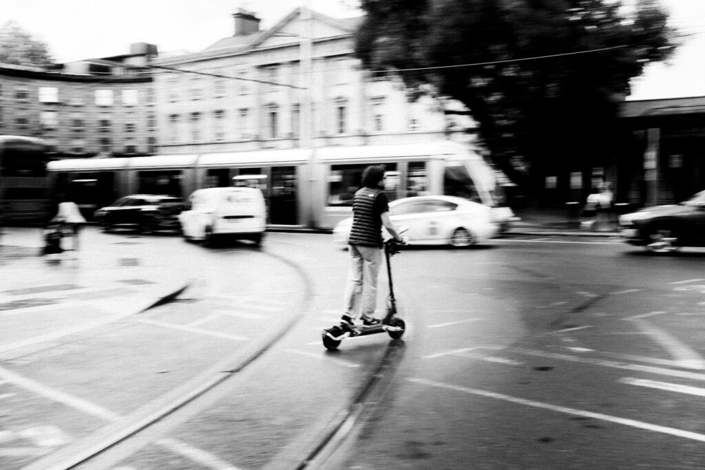 Persona conduce un scooter eléctrico por una calle de la ciudad, imagen desenfocada