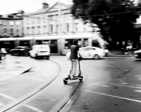 Persona conduce un scooter eléctrico por una calle de la ciudad, imagen desenfocada